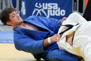 A male judo competitor grapples with his opponent. 
