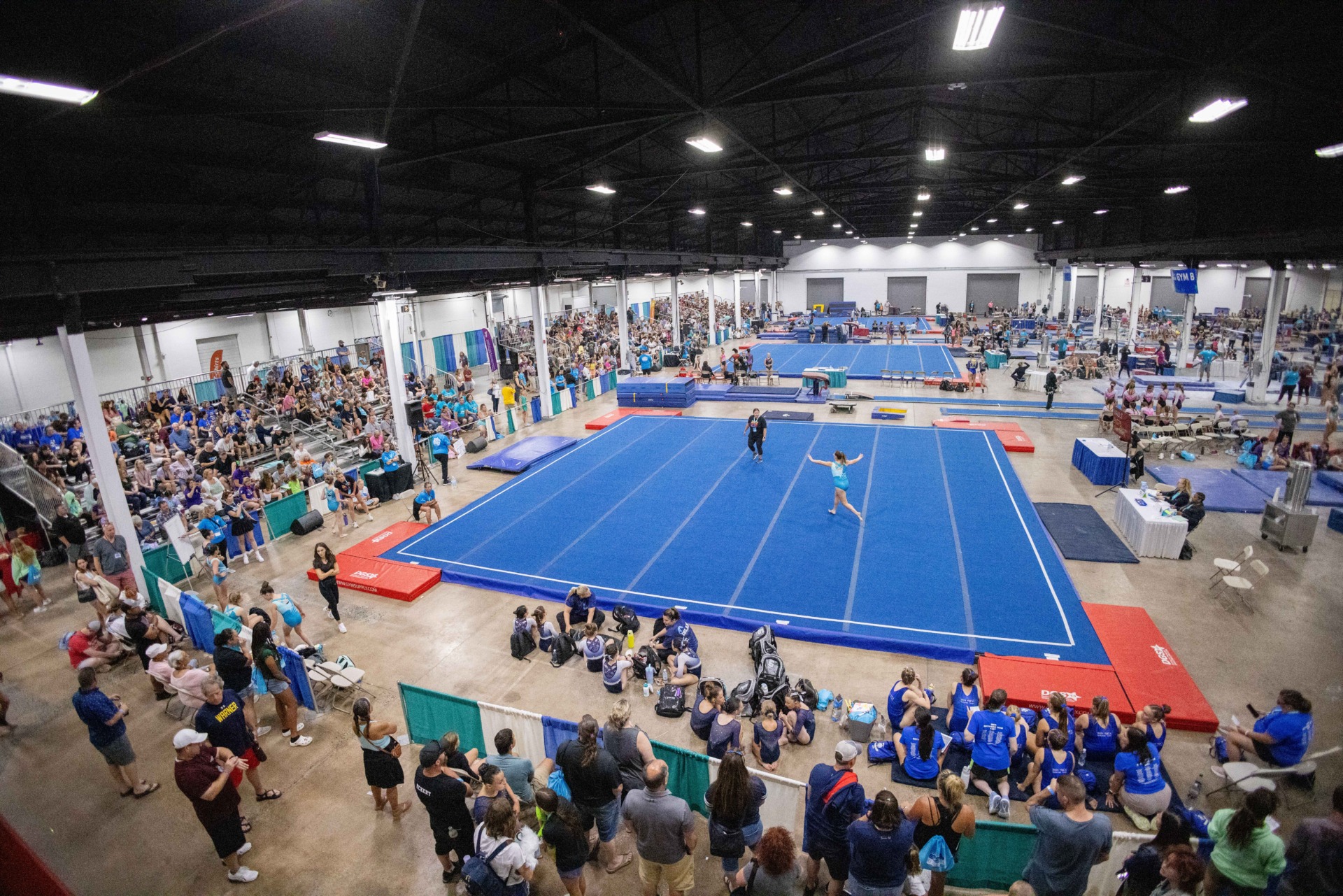 A crowd watching a gymnastics competition in an indoor space.