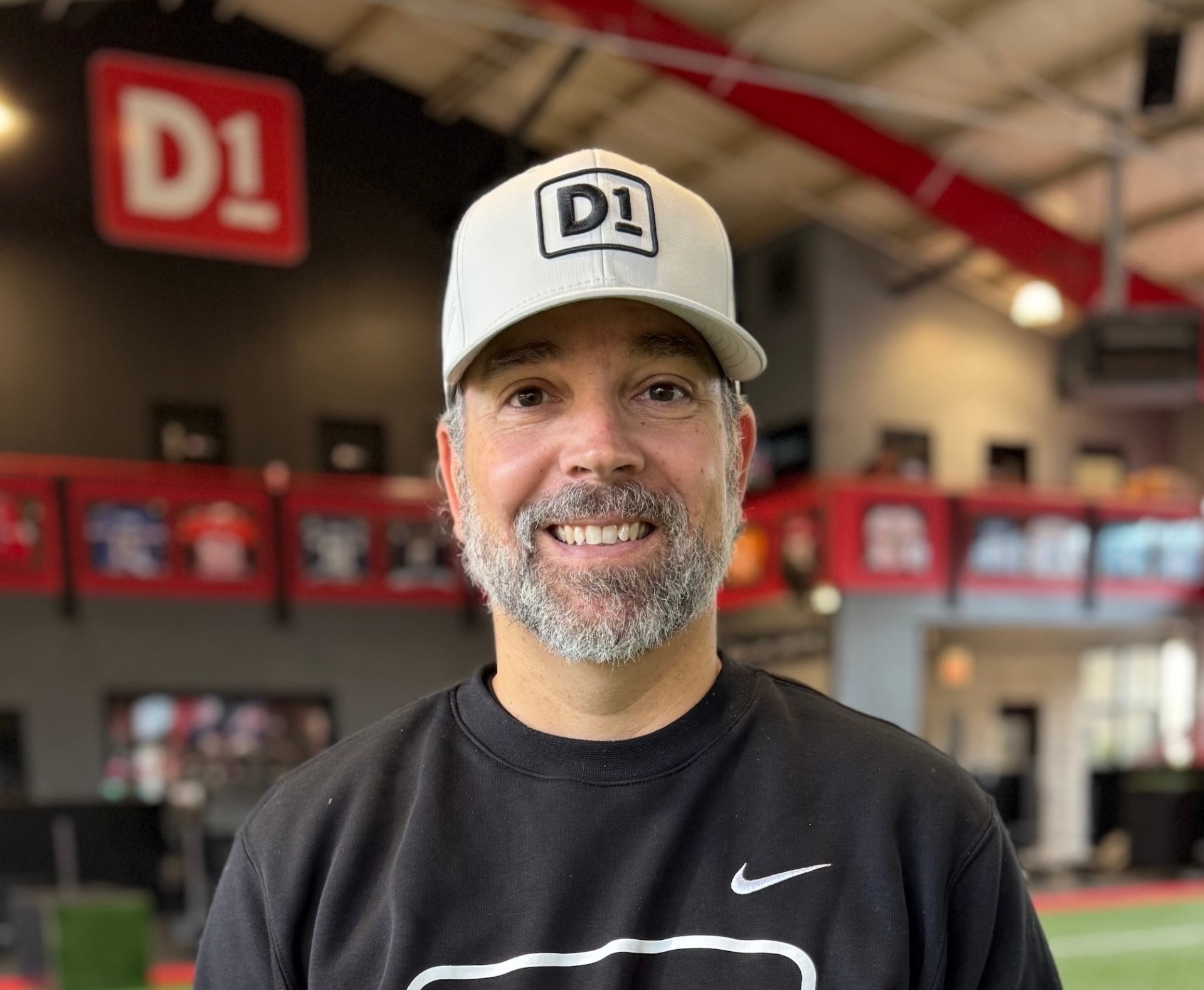 A photo of Dom Bonvissuto in a baseball cap and a black D1-branded sweatshirt.