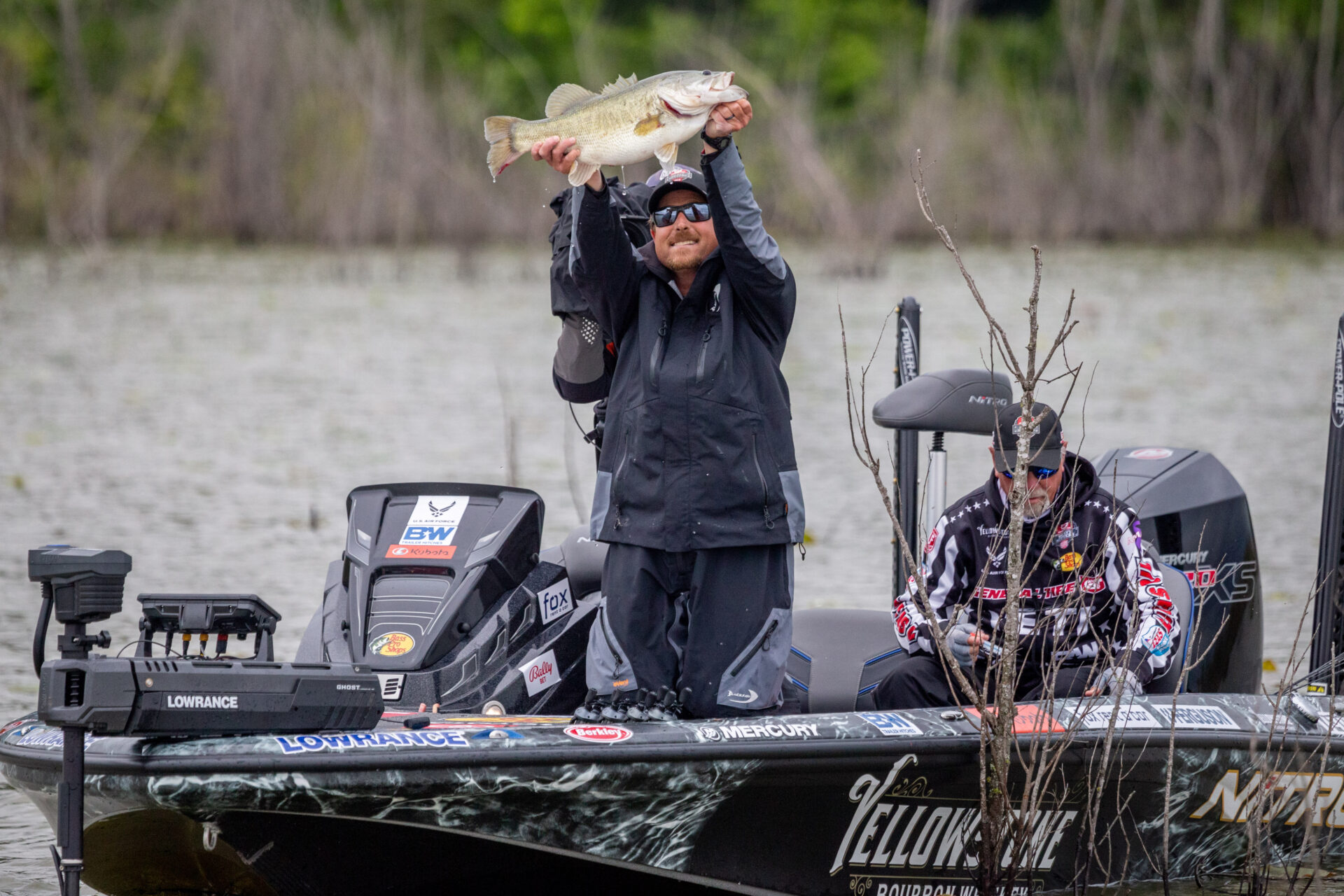 Bryan Thrift holding up a bass on the water.