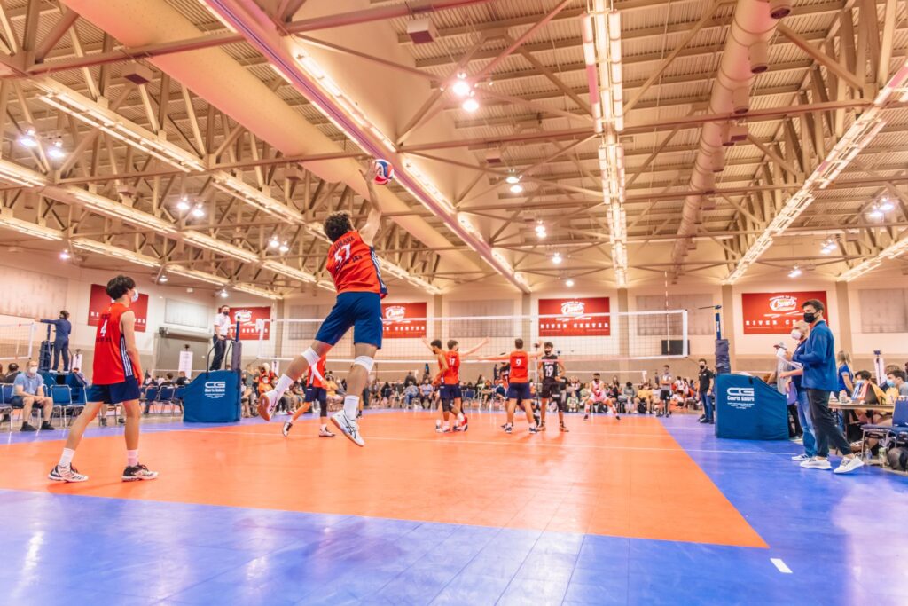 A volleyball player jumps in the air to serve a ball during a game at Baton Rouge's Raising Cane's River Center