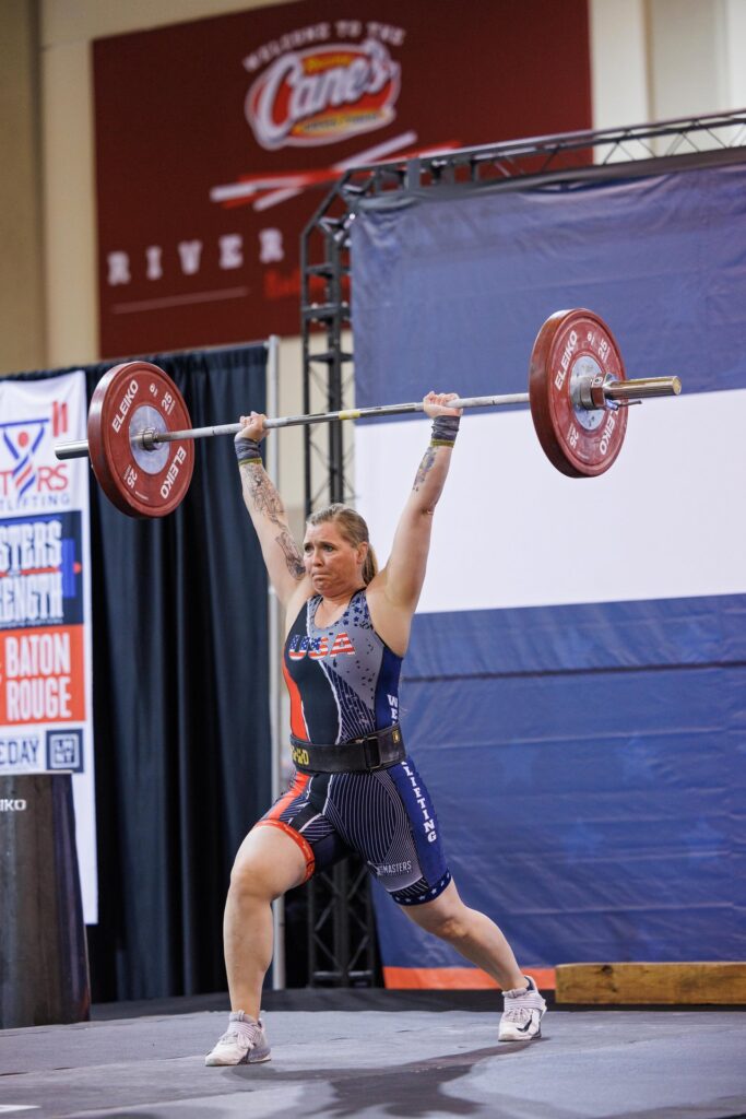 A female weightlifter holds a barbell over her head