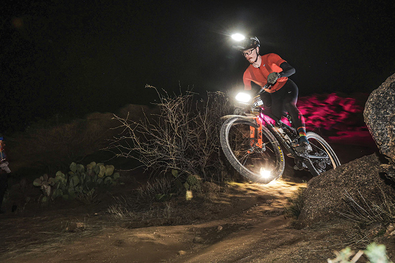 A mountain biker at night with a headlight.