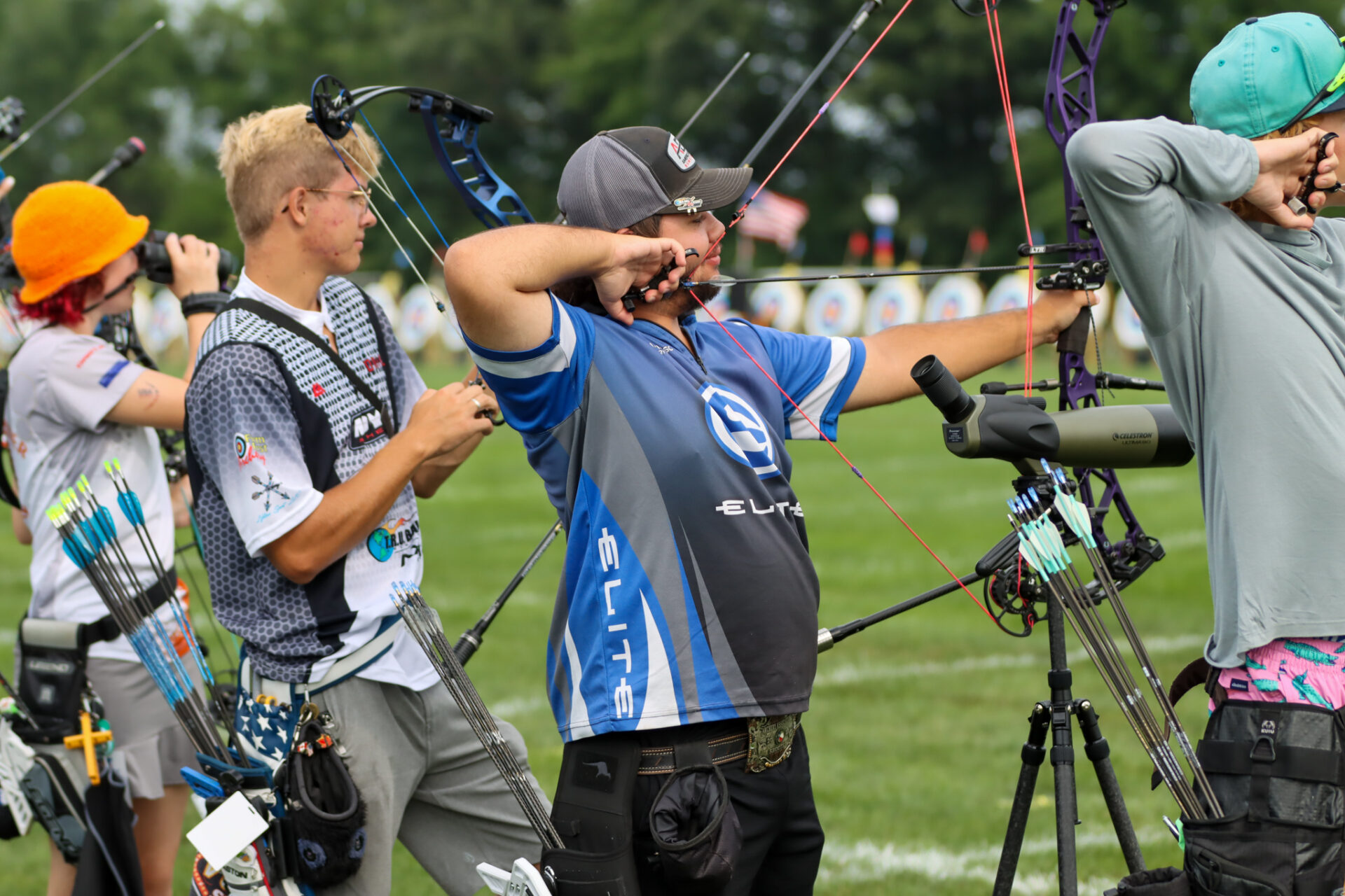 Four people lined up for a round of archery.