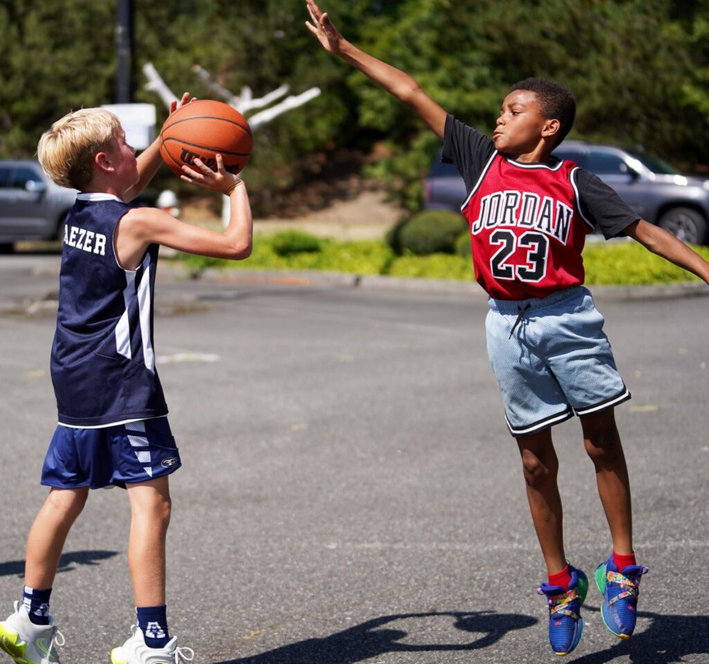 Two boys playing basketball outdoors.