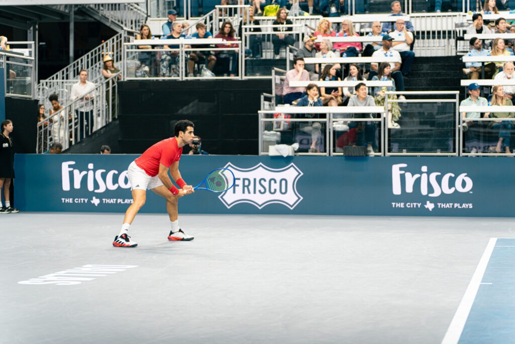 A tennis player on the court gets ready to receive the ball.