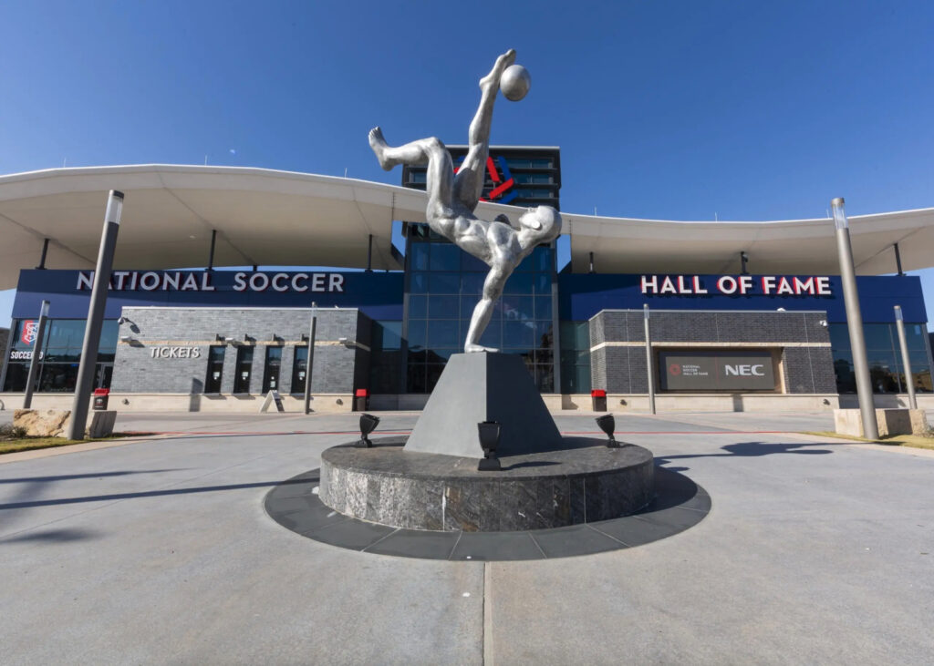 The exterior of the National Soccer Hall of Fame shows a statue of a player doing a bicycle kick.
