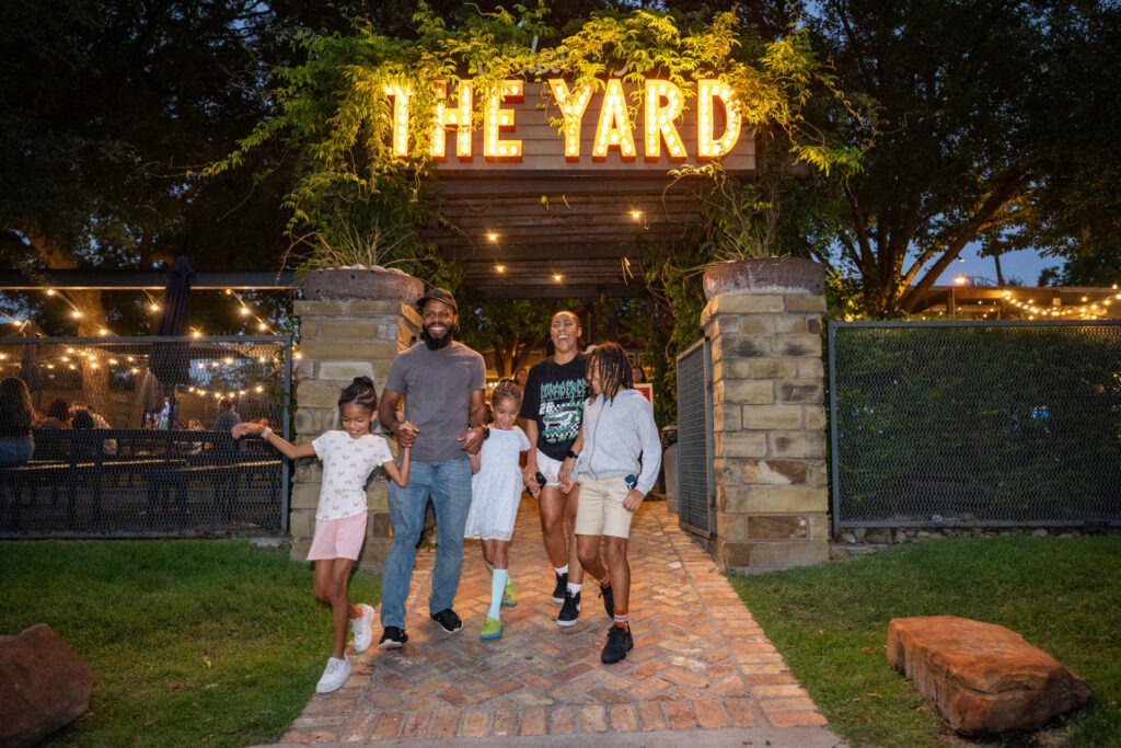 A family of five walk hand in hand in downtown McKinney, Texas.