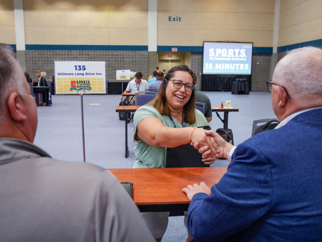 Two people seated at a table are shaking hands